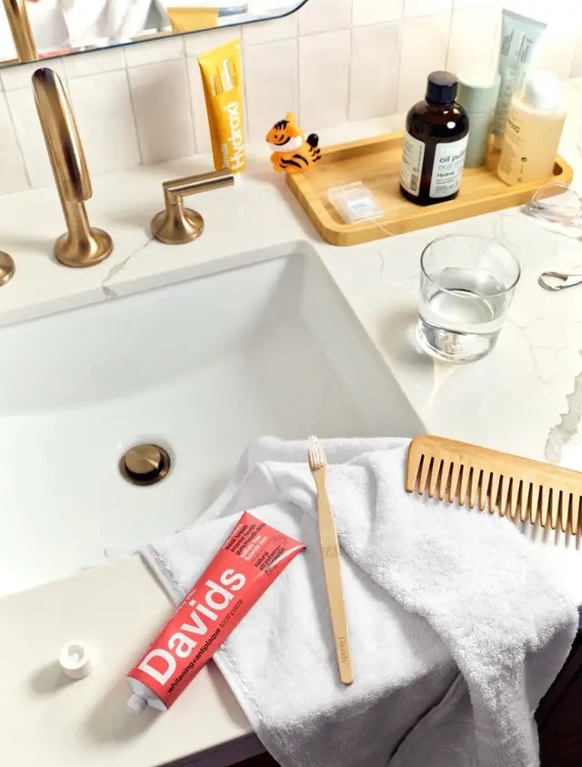 Davids toothpaste and a bamboo toothbrush on a bathroom vanity