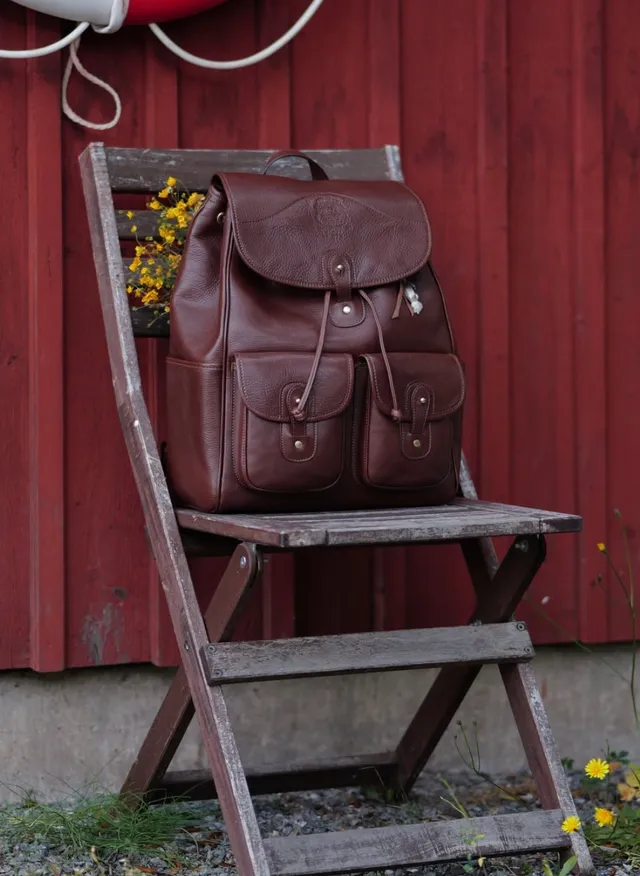 A brown Ghurka leather backpack on a wooden chair