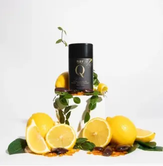 A black Play Pits Queen deodorant on a white block surrounded by lemons and leaves