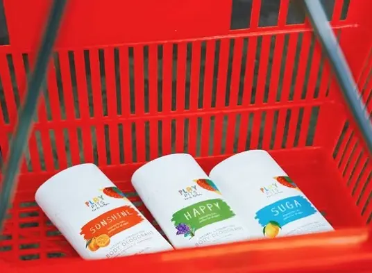 Play Pits Sunshine, Happy and Suga deodorants lying in a red shopping basket
