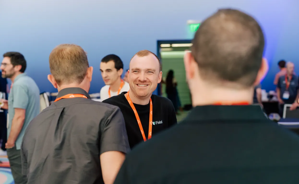 A smiling Fiskal team member in conversation with two attendees at Cin7 Summit